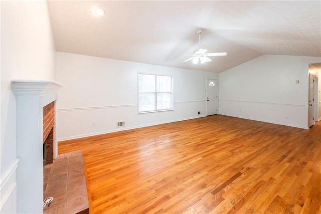 unfurnished living room with lofted ceiling, a brick fireplace, ceiling fan, and light hardwood / wood-style floors