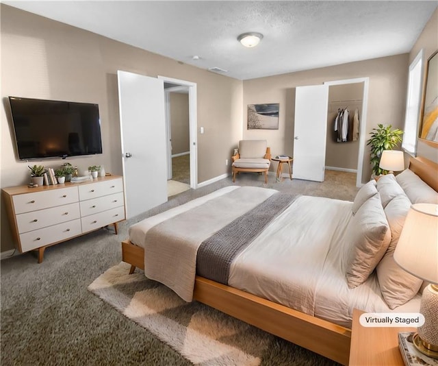 carpeted bedroom with a textured ceiling, a walk in closet, and a closet