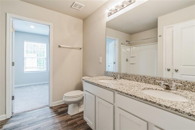 bathroom featuring double vanity, toilet, and wood-type flooring