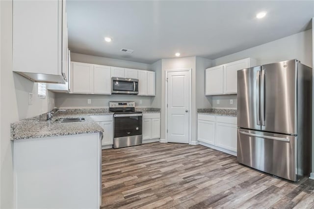 kitchen featuring hardwood / wood-style flooring, white cabinetry, and appliances with stainless steel finishes