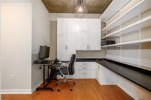 office area featuring light wood-style floors, baseboards, and built in study area