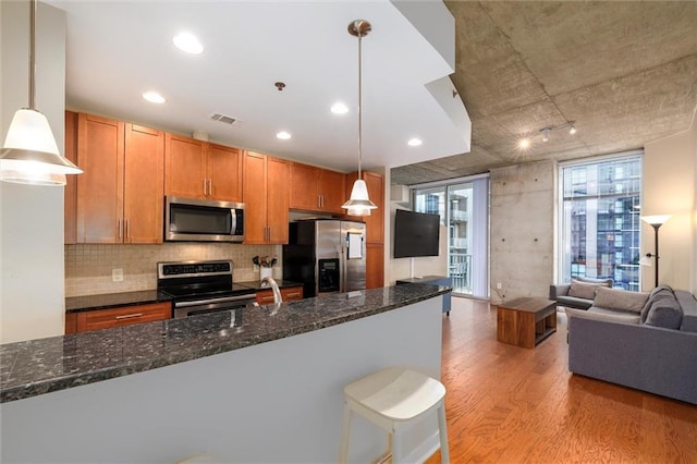 kitchen featuring stainless steel appliances, visible vents, light wood-style floors, open floor plan, and decorative light fixtures