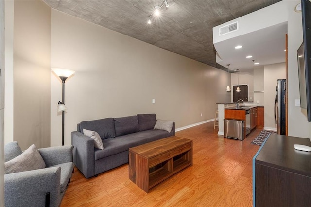 living area with light wood-style floors, baseboards, and visible vents