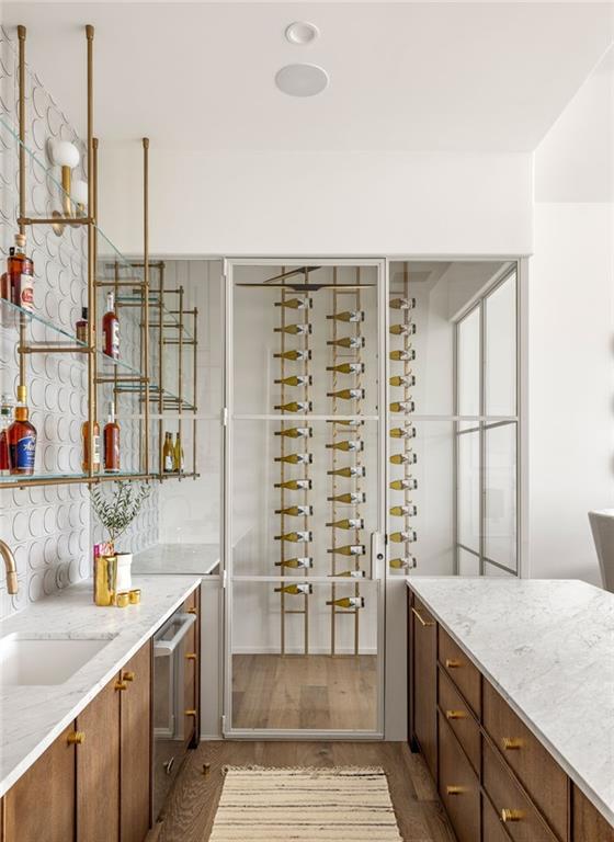 interior space featuring stainless steel dishwasher, decorative backsplash, light stone countertops, and sink