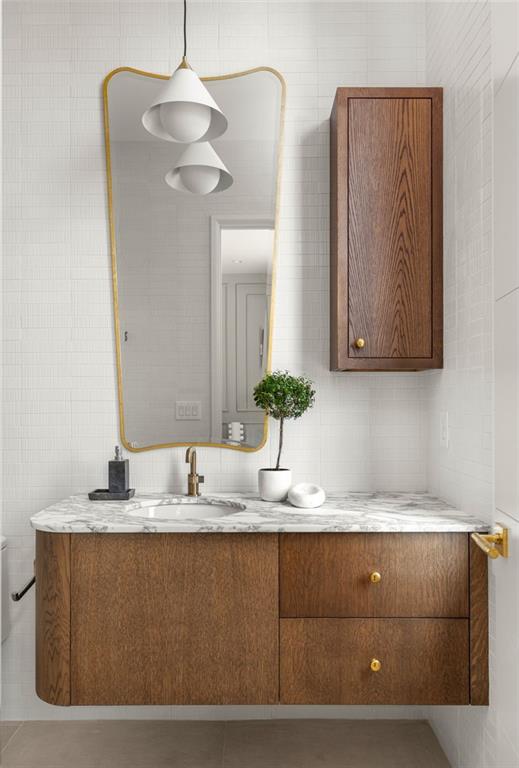 bathroom featuring tile patterned flooring, vanity, and tile walls