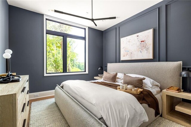 bedroom featuring wood-type flooring, ensuite bathroom, and multiple windows