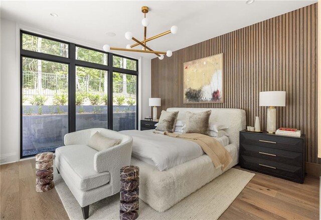 bedroom featuring expansive windows, access to exterior, multiple windows, and light hardwood / wood-style flooring