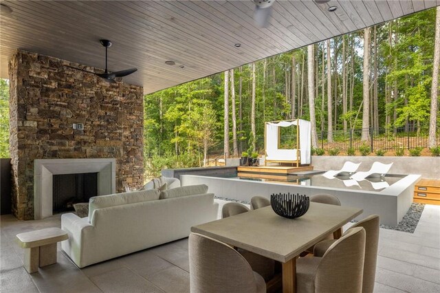 living room featuring an outdoor stone fireplace, wooden ceiling, ceiling fan, and a healthy amount of sunlight