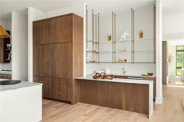 bar with decorative backsplash and light hardwood / wood-style floors