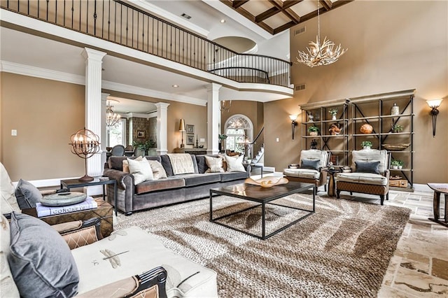 living room featuring an inviting chandelier, ornamental molding, a towering ceiling, and ornate columns