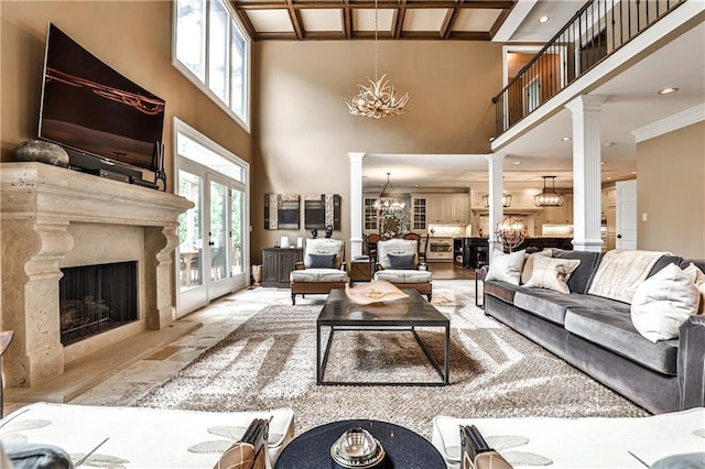 living area with ornate columns, a towering ceiling, and a notable chandelier