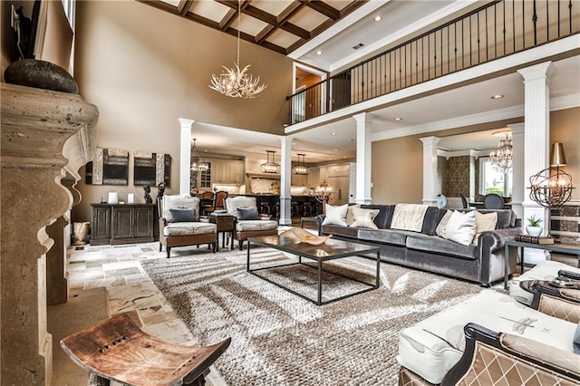 living room with a towering ceiling, a notable chandelier, ornamental molding, coffered ceiling, and ornate columns