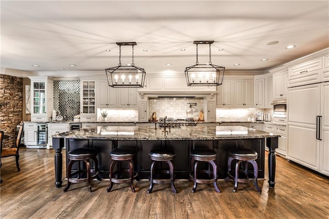 kitchen featuring beverage cooler, dark wood-style flooring, built in appliances, and a spacious island