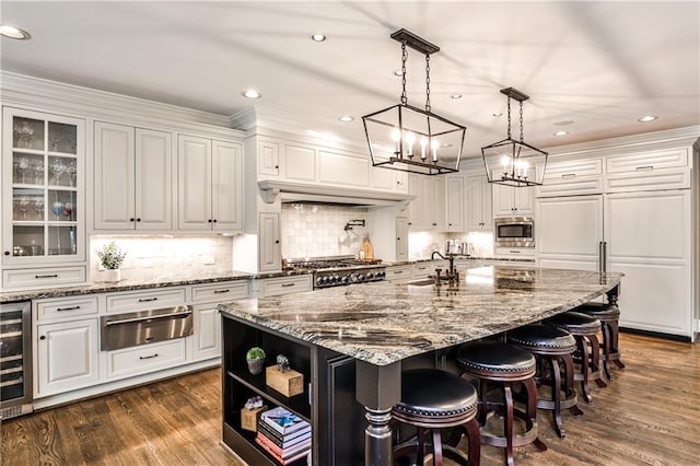 kitchen featuring a warming drawer, stainless steel microwave, and white cabinetry