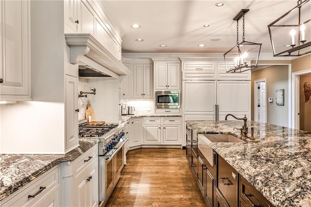 kitchen featuring pendant lighting, appliances with stainless steel finishes, wood finished floors, an inviting chandelier, and white cabinetry