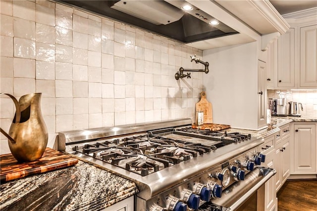 kitchen with white cabinets, dark wood-style flooring, light stone countertops, high end range, and tasteful backsplash