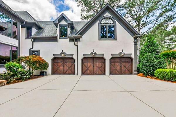 french country home with stucco siding, concrete driveway, and a garage