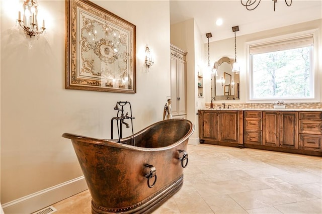 bathroom with double vanity, baseboards, a sink, and a soaking tub