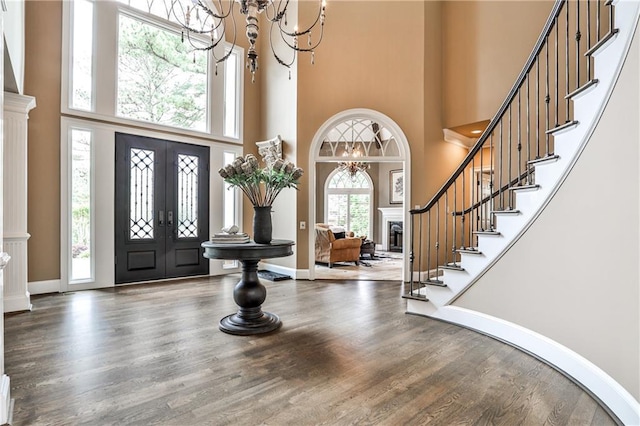 foyer entrance featuring wood finished floors, a high ceiling, stairway, french doors, and a notable chandelier