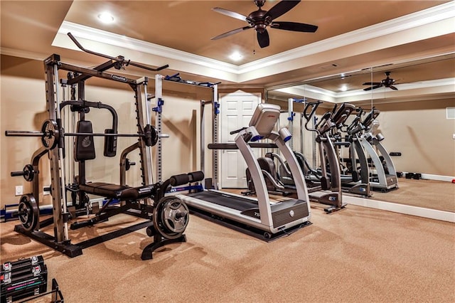 gym featuring a ceiling fan, ornamental molding, and a raised ceiling
