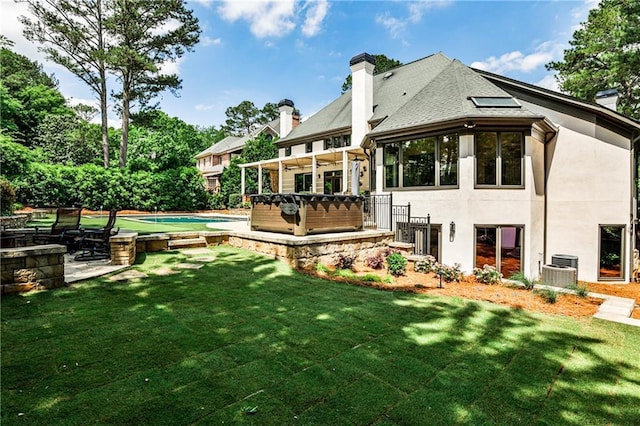 back of house featuring a hot tub, a yard, and a chimney