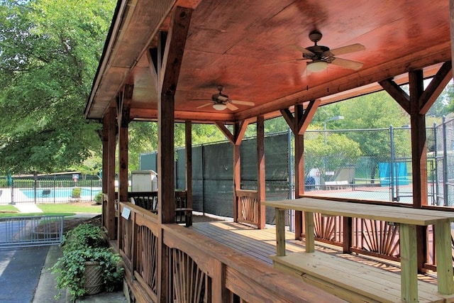 deck featuring fence, a pool, and ceiling fan