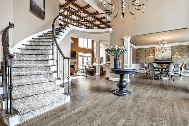 foyer entrance with an inviting chandelier, stairs, a towering ceiling, and wood finished floors