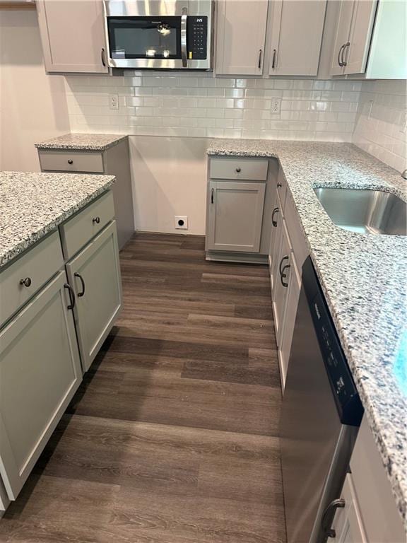 kitchen featuring appliances with stainless steel finishes, light stone countertops, and dark hardwood / wood-style flooring