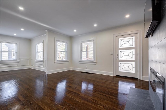 foyer featuring crown molding, recessed lighting, dark wood-style floors, and a tile fireplace