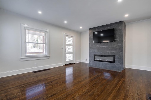 unfurnished living room featuring a tiled fireplace, visible vents, plenty of natural light, and wood finished floors