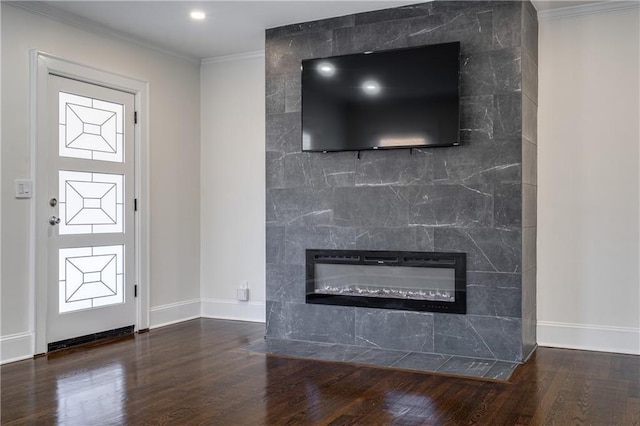 interior space featuring wood finished floors, baseboards, recessed lighting, a tile fireplace, and crown molding