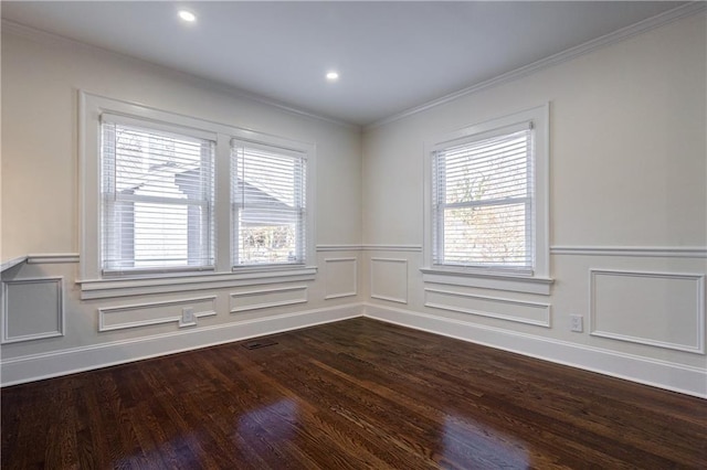 empty room with dark wood finished floors, plenty of natural light, a decorative wall, and ornamental molding