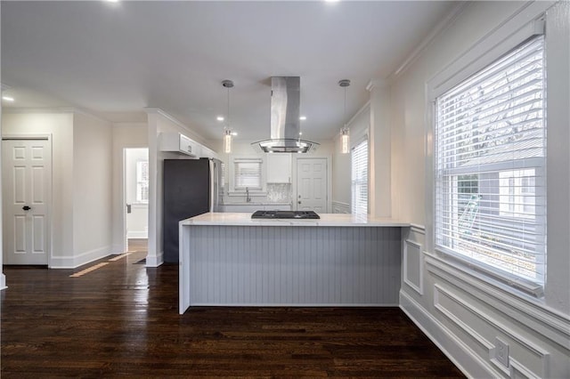 kitchen featuring island exhaust hood, dark wood-style floors, white cabinetry, freestanding refrigerator, and a peninsula