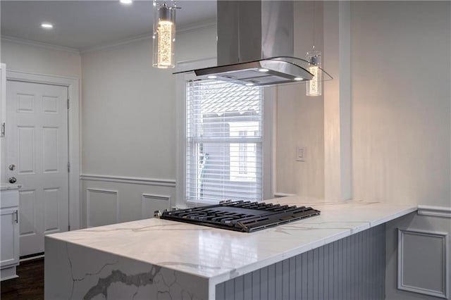 kitchen featuring light stone counters, ornamental molding, black gas cooktop, wall chimney range hood, and a decorative wall