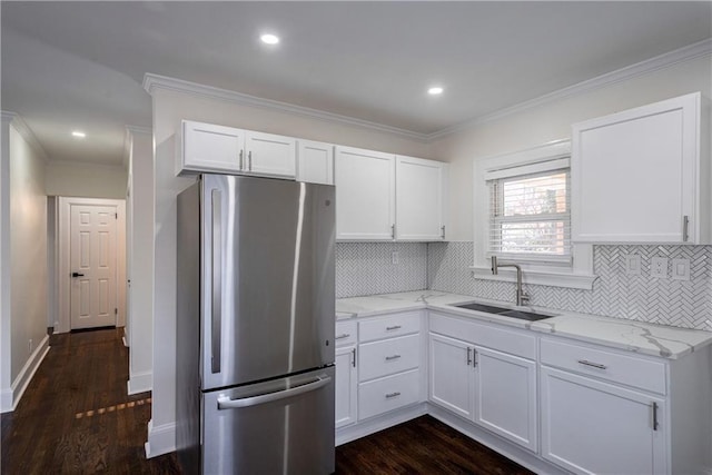 kitchen featuring white cabinetry, light stone countertops, freestanding refrigerator, and a sink