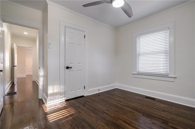 unfurnished room with a ceiling fan, baseboards, visible vents, dark wood finished floors, and ornamental molding