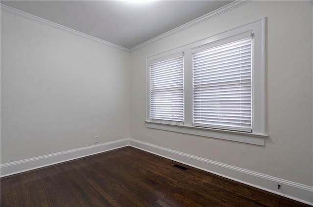 spare room with visible vents, baseboards, dark wood finished floors, and ornamental molding