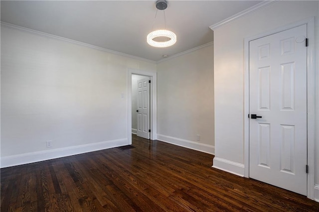 empty room with dark wood finished floors, crown molding, and baseboards