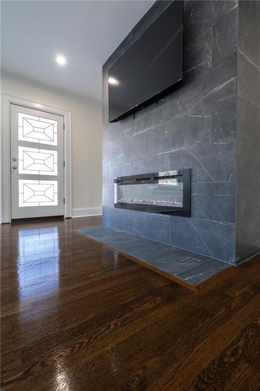 details featuring a tile fireplace, baseboards, and wood finished floors