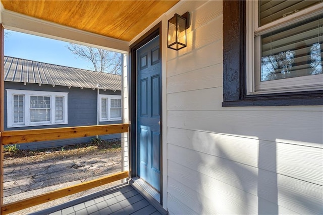 view of exterior entry with covered porch and metal roof