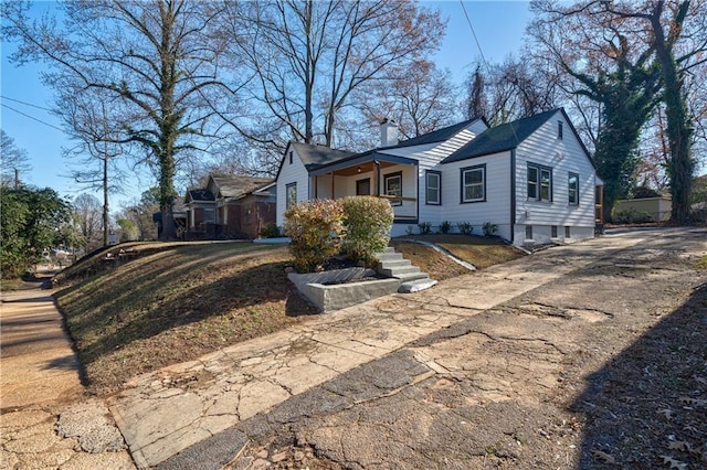 view of front of house with a porch, driveway, and a chimney