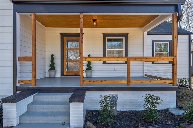 doorway to property with roof with shingles and covered porch