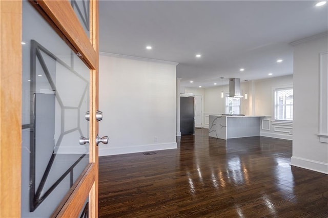 unfurnished living room featuring recessed lighting, dark wood-type flooring, baseboards, and ornamental molding