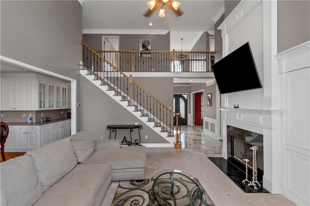 5810 Old Mill Trce, Lithonia, GA 30038 - living room featuring ceiling fan, a high ceiling, stairs, a fireplace with flush hearth, and crown molding