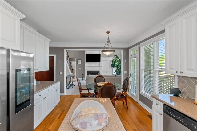5810 Old Mill Trce, Lithonia, GA 30038 - kitchen featuring appliances with stainless steel finishes, light countertops, light wood-style flooring, white cabinetry, and ornamental molding