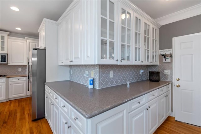 5810 Old Mill Trce, Lithonia, GA 30038 - kitchen with appliances with stainless steel finishes, white cabinetry, ornamental molding, wood finished floors, and tasteful backsplash