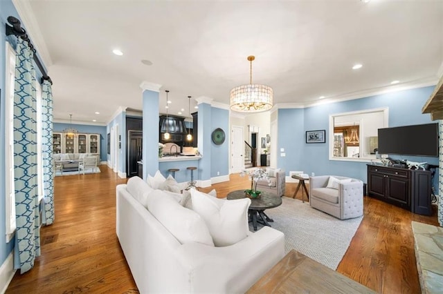 living room featuring dark hardwood / wood-style flooring, crown molding, and a notable chandelier