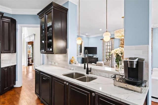 kitchen featuring crown molding, decorative light fixtures, sink, hardwood / wood-style floors, and dark brown cabinetry