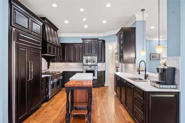 kitchen with pendant lighting, dark brown cabinetry, tasteful backsplash, sink, and high quality appliances