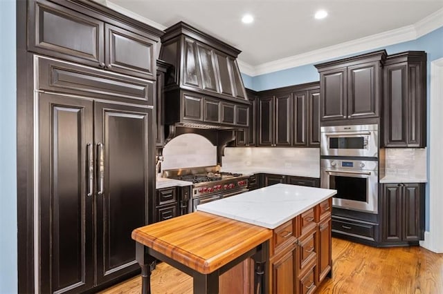 kitchen featuring dark brown cabinetry, backsplash, ornamental molding, light wood-type flooring, and high quality appliances